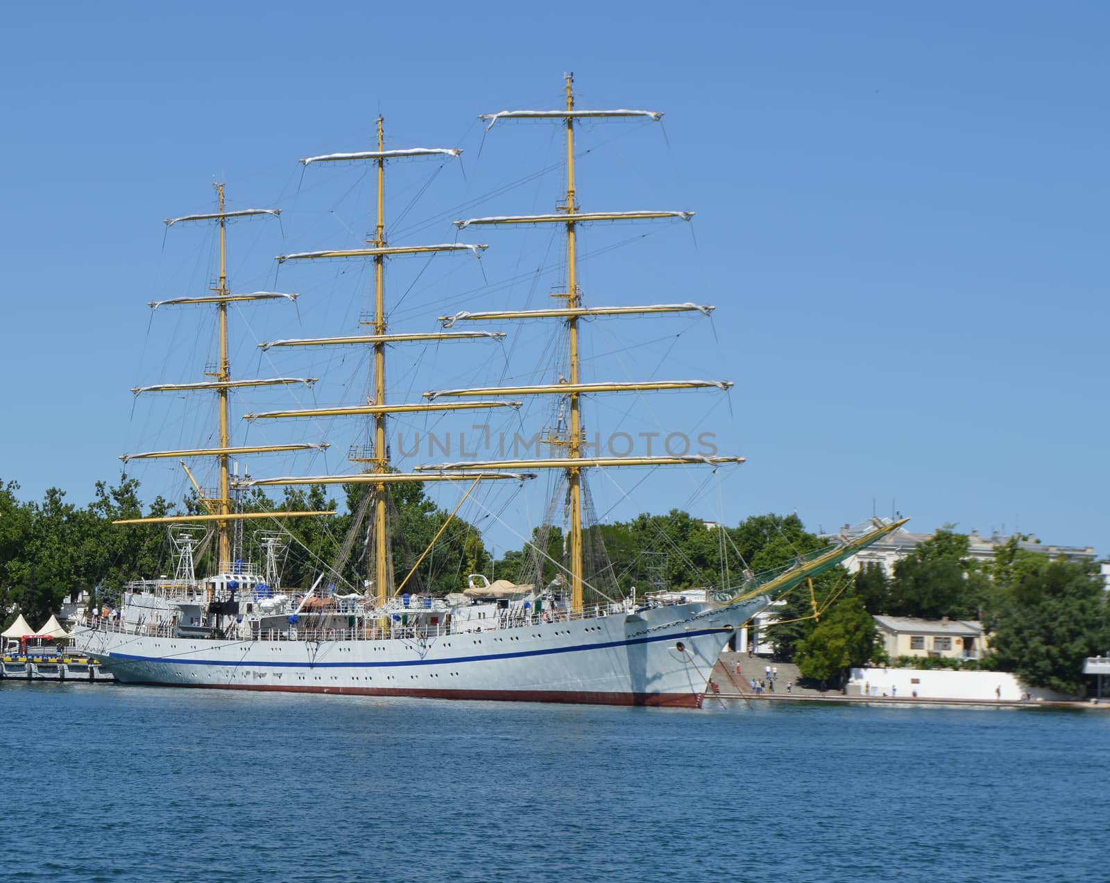 Old yacht with lowered sails moored in the port.