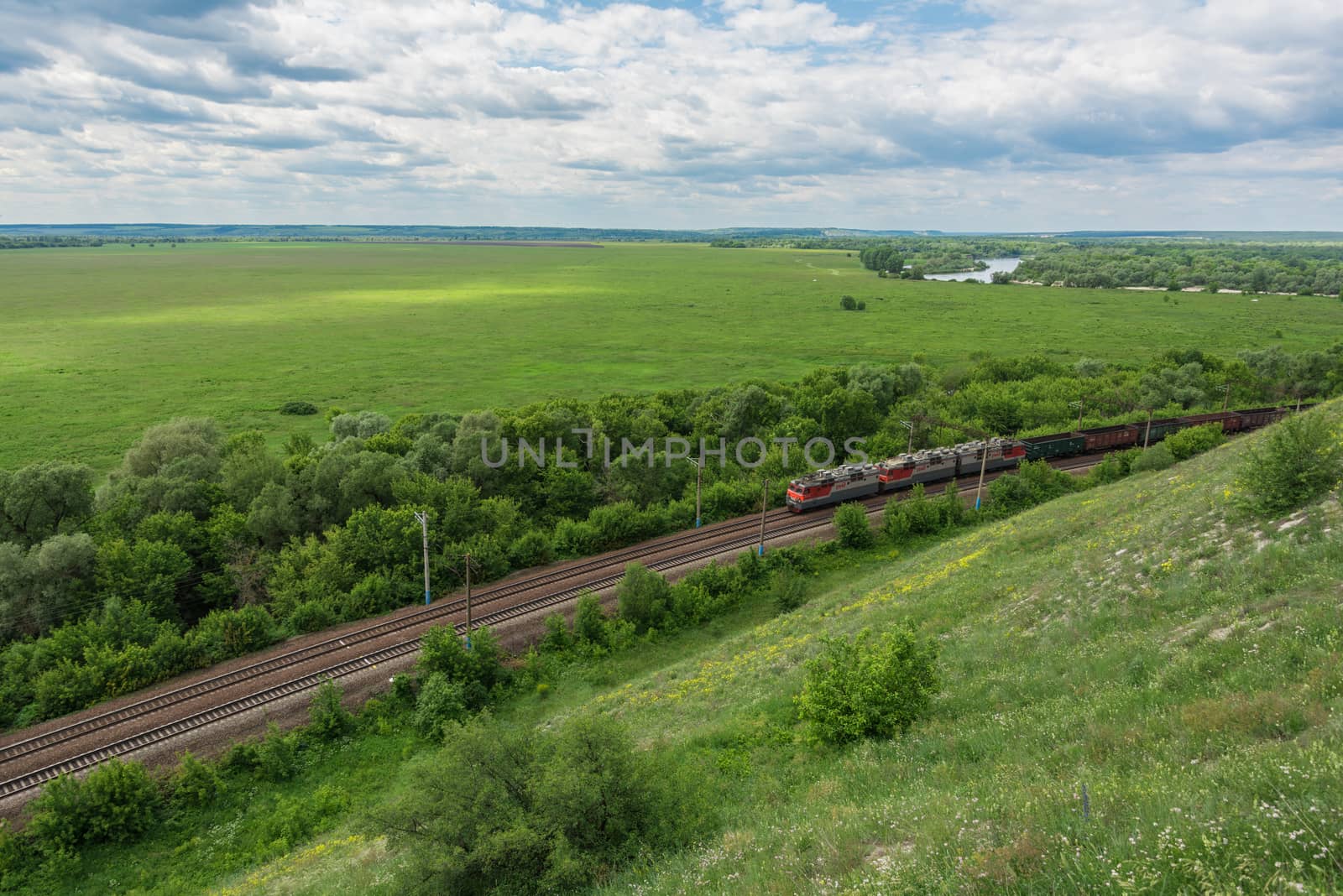 Freight train with locomotives passing by rail in Russia, along the typical Russian landscape, top view.