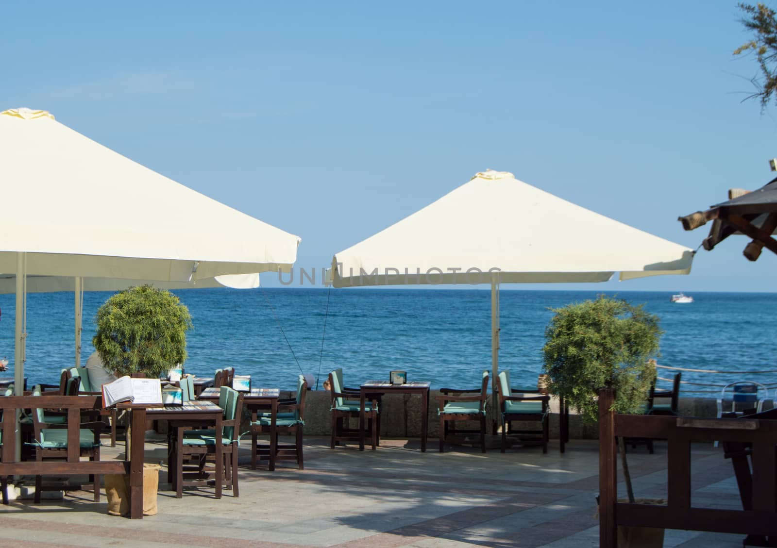 Tables and umbrellas at the seaside restaurant on a Sunny summer day.