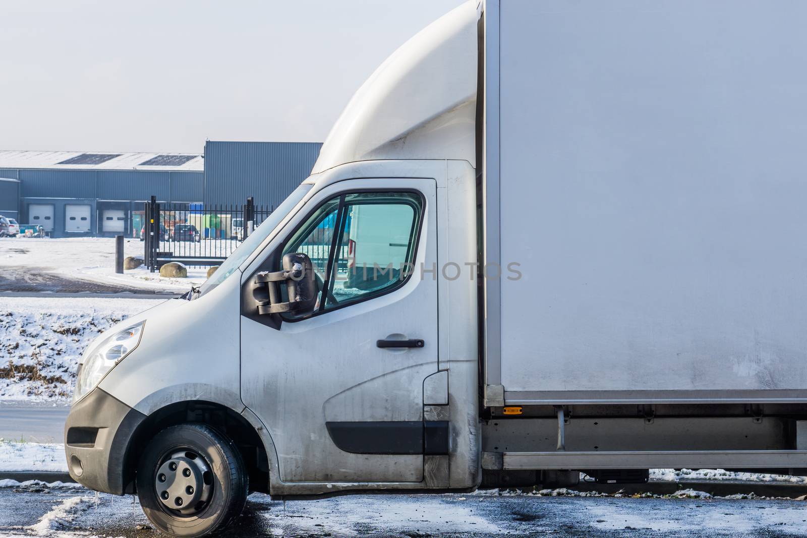 white parked van during winter with a warehouse in the background, logistics and transportation vehicle