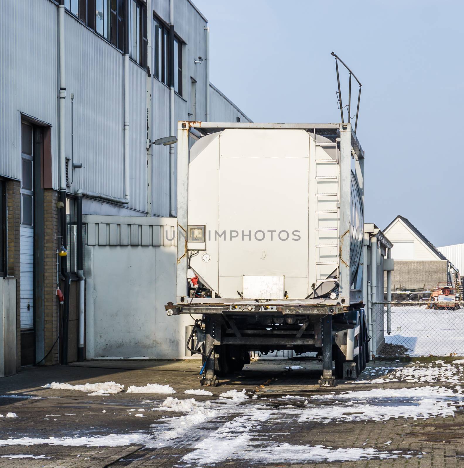 parked tank trailer at the door of a warehouse, outdoor exterior of a workplace by charlottebleijenberg