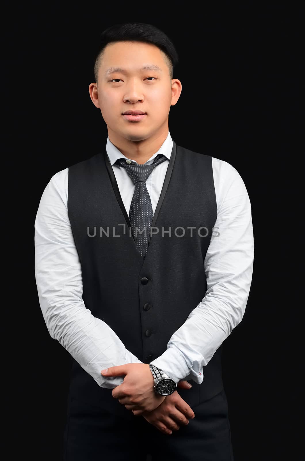 Beauty portrait of a young man of Asian appearance who stands on a black background in the Studio