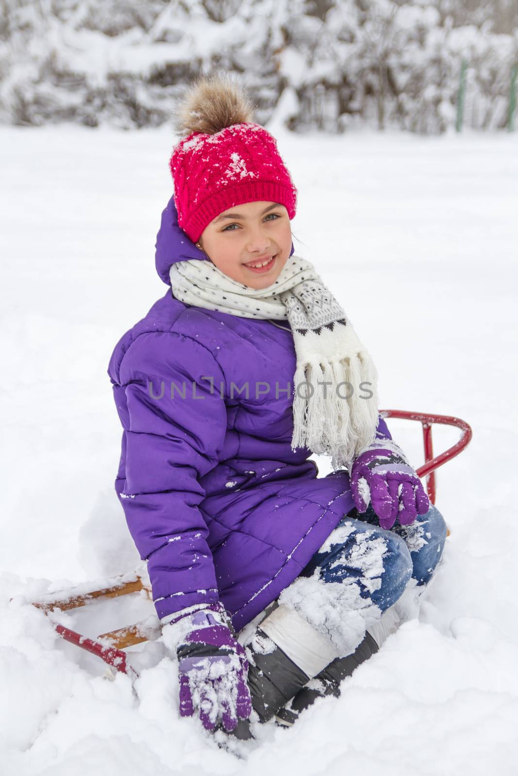 Smiling child girl in snowy park on sledge