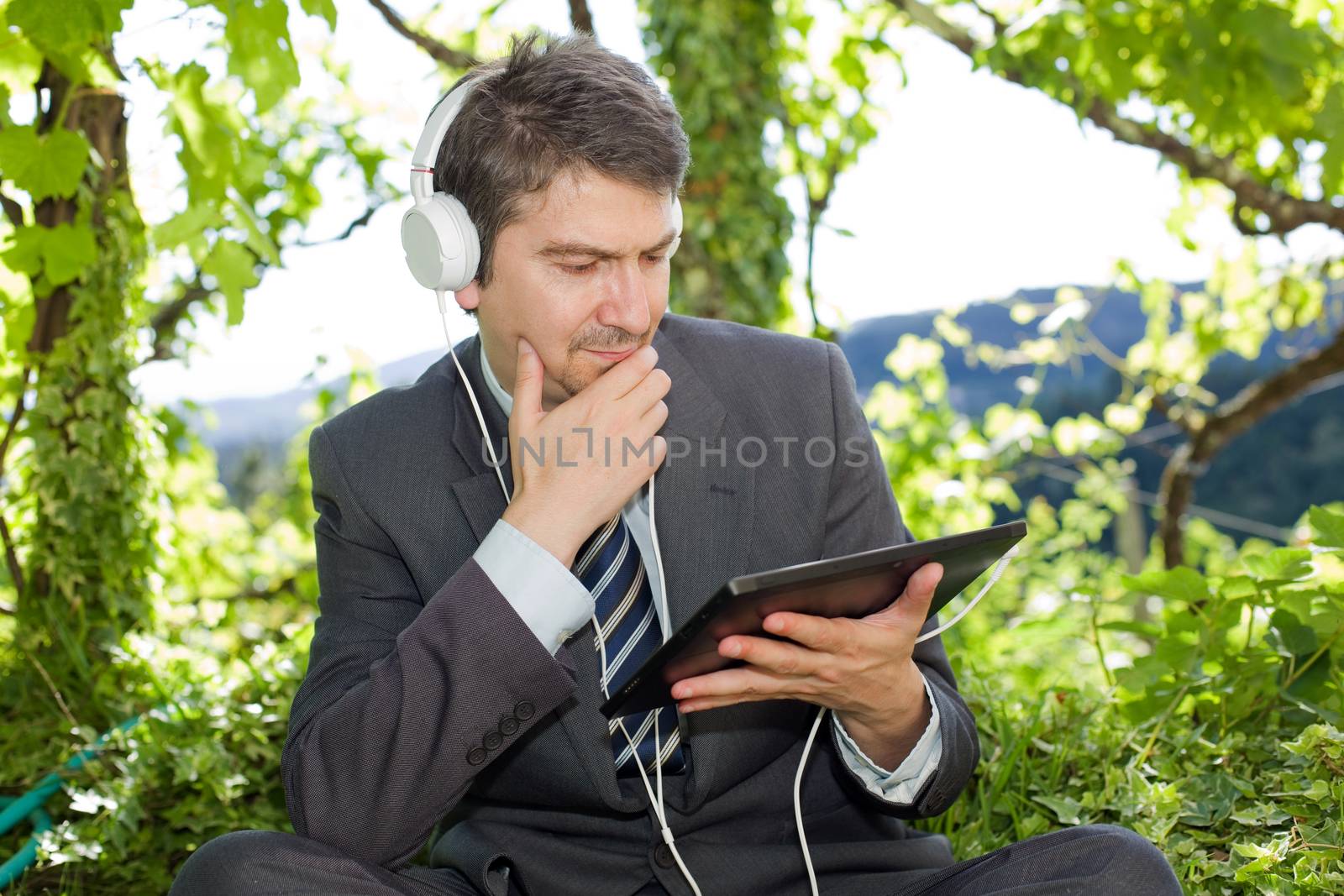 happy businessman with digital tablet and headphones, outdoors