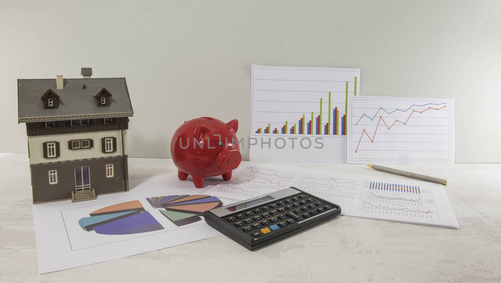 model of a business and financial investment with a model of a house or planning of the construction of a house with money pig and graphics
