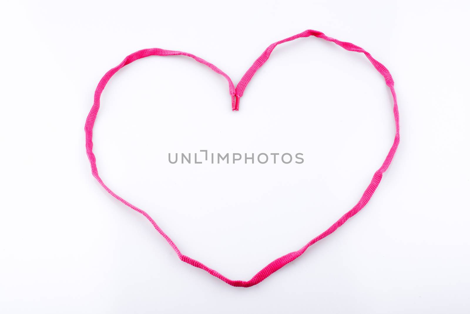 Heart shaped made by the help of a pink sholace on white background