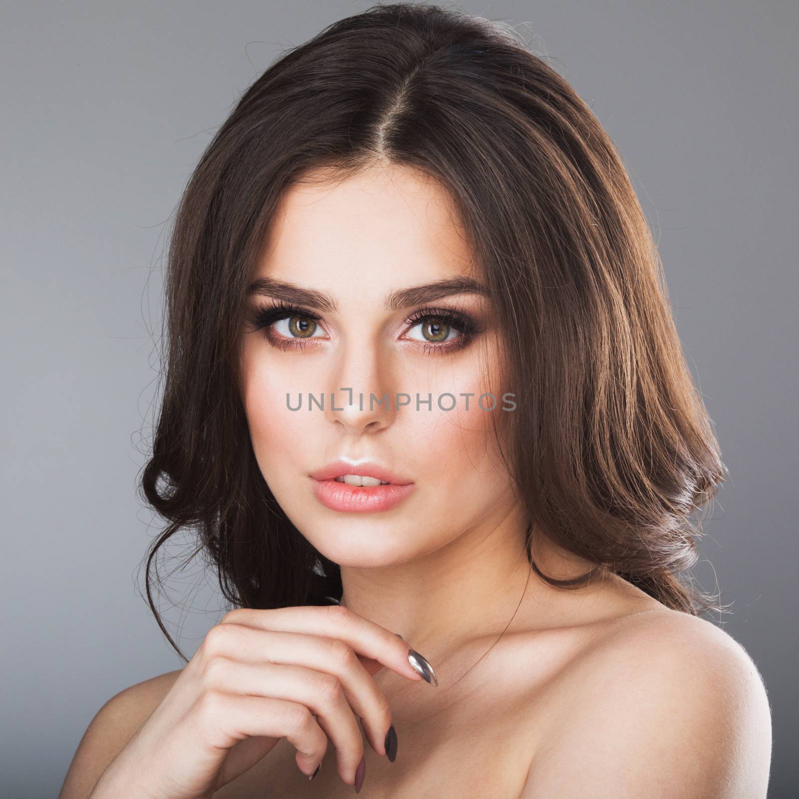 Portrait of beautiful young woman with long brown hair, over grey background