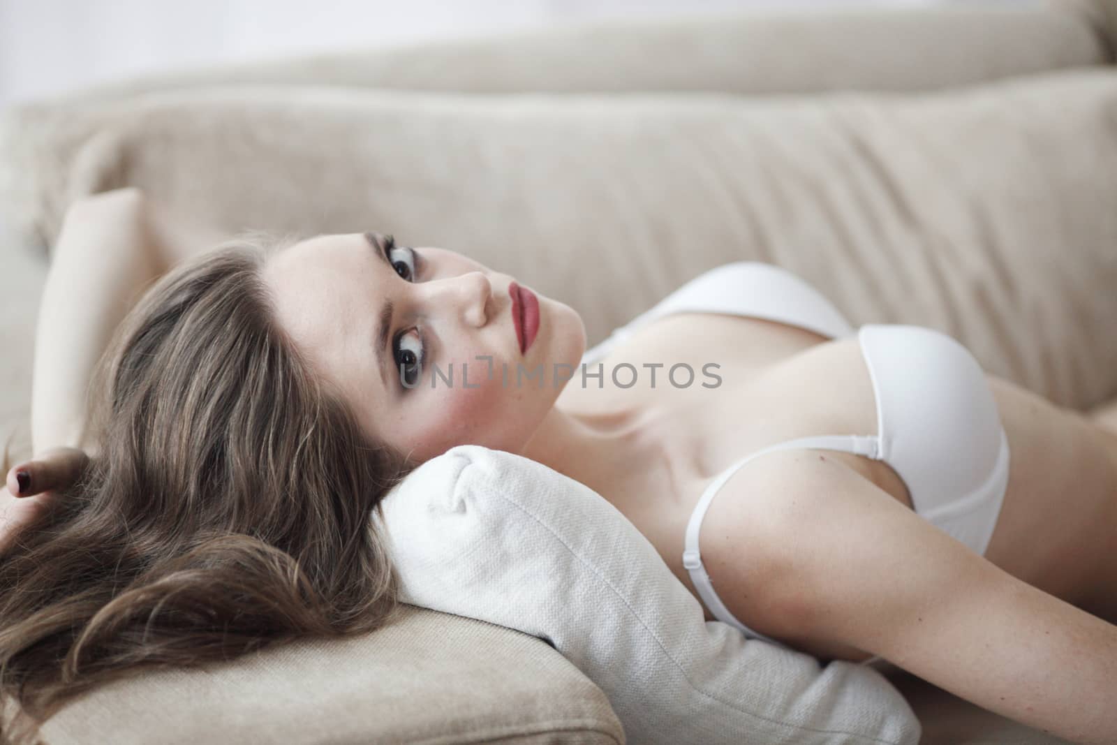 Portrait of beautiful young woman in lingerie on sofa