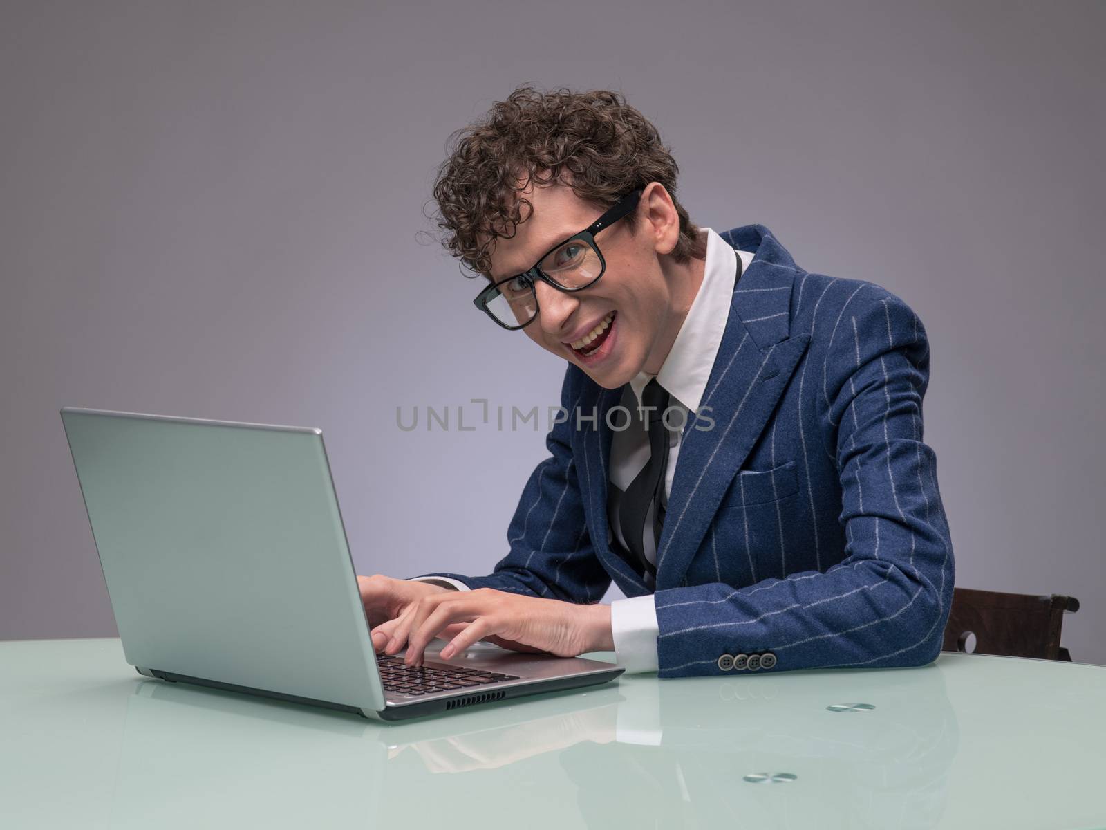 Funny business man geek using laptop with evil genius facial expression