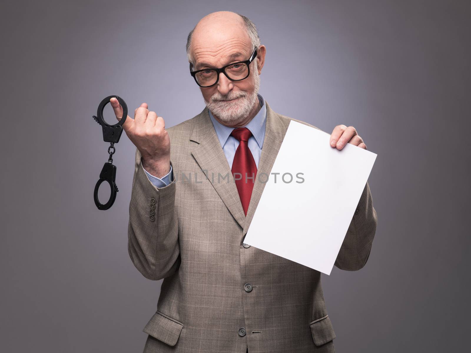 Senior business man with handcuffs and blank contract paper hints at danger of financial crimes