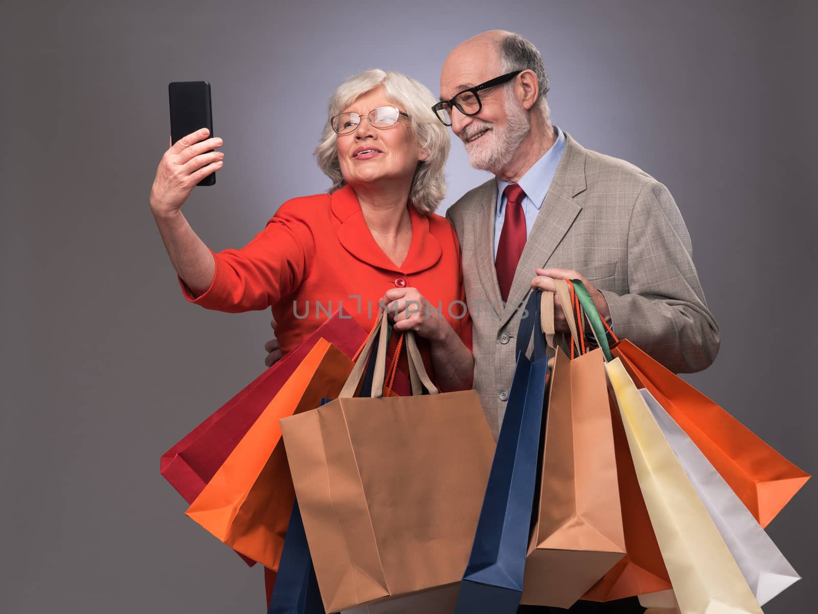 Happy couple taking selfie after shopping with many bags