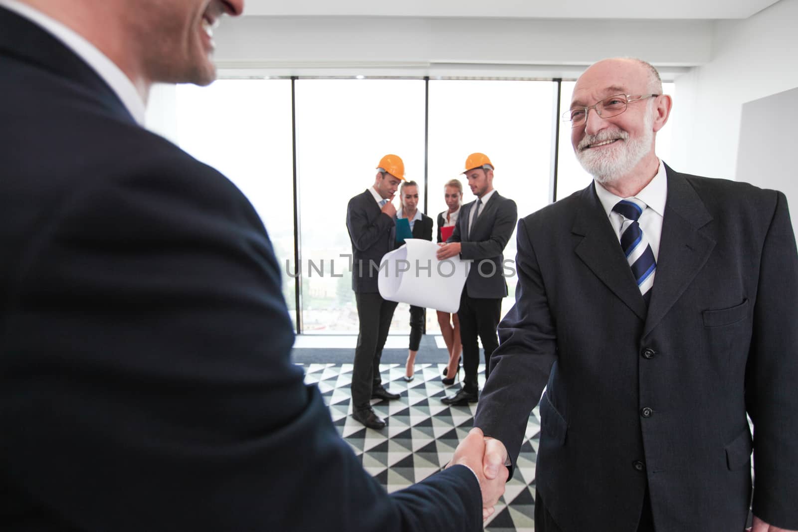 Business people shaking hands at meeting of architects and investors in office