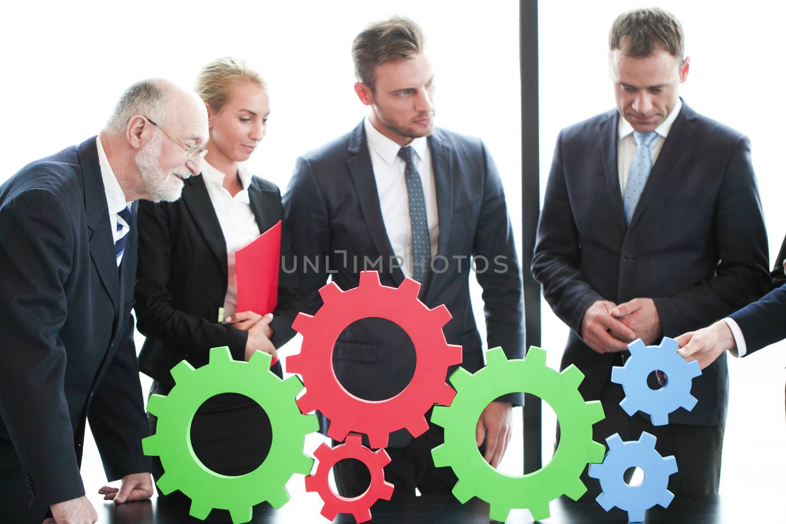 Business people assembling cogwheels, teamwork concept