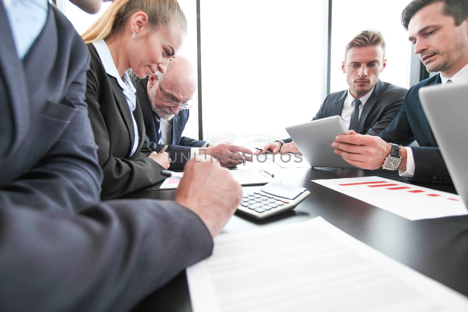 Group of people in office at business meeting working with documents reports and computers