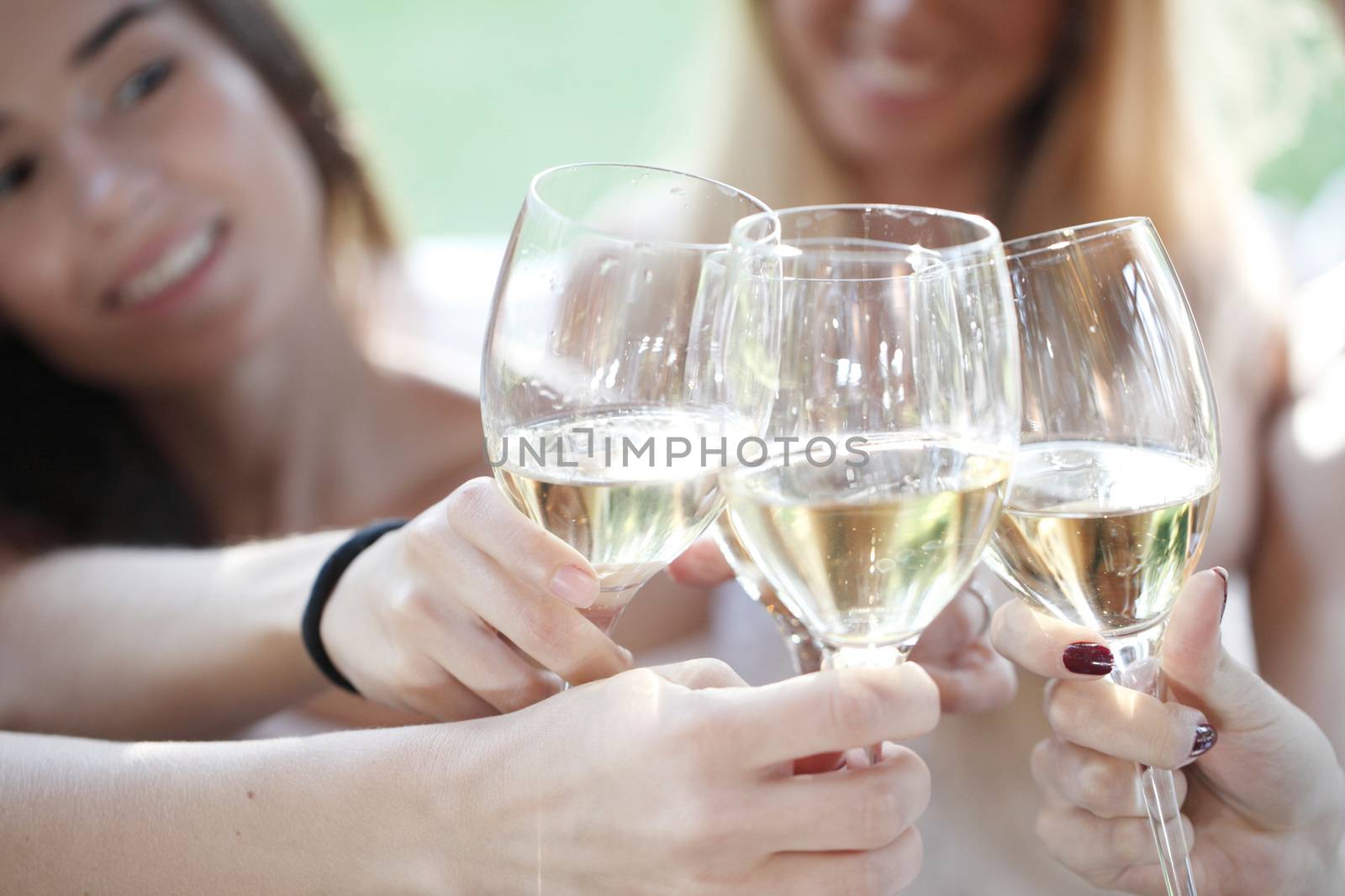 Happy female friends toasting white wine outdoors