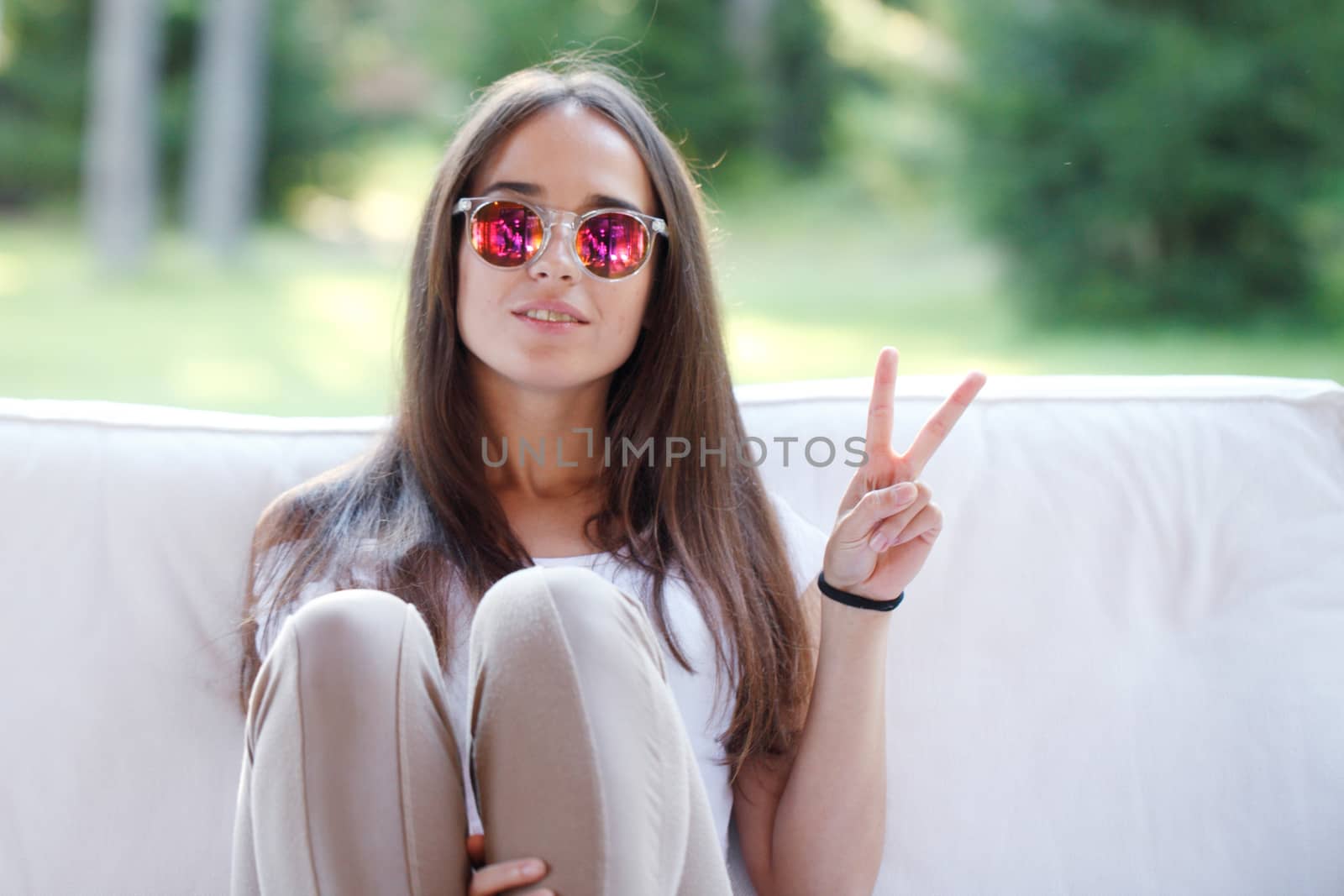 Young beautiful girl show victory sign sitting outdoors