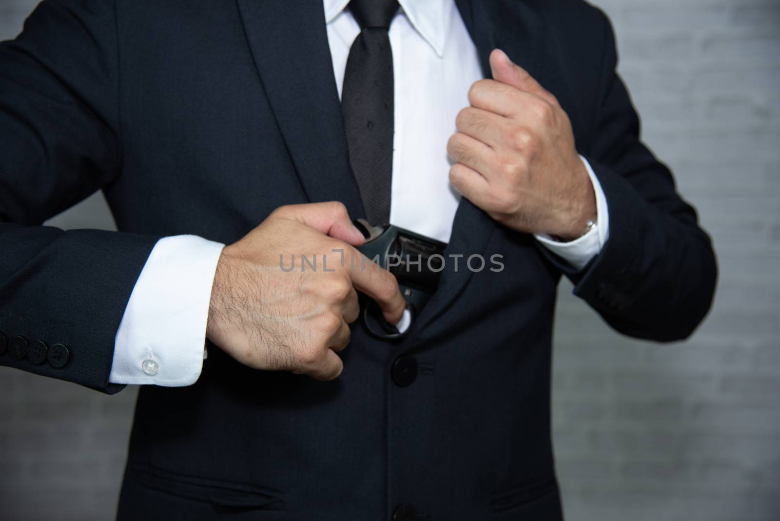 Businessman holding the gun on gray background by Wmpix