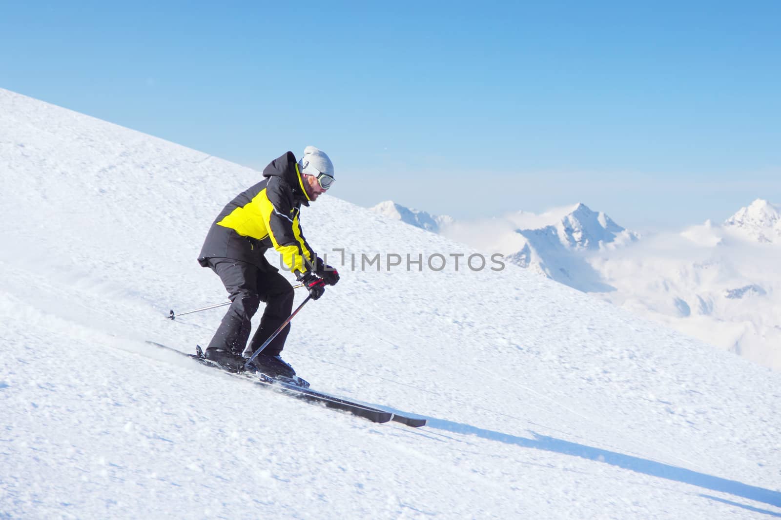 Alpine skier on piste running downhill in beautiful Alpine landscape. Blue sky on background. Free copy space for text