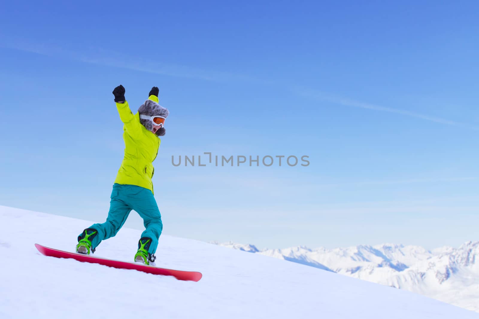 Girl snowboarder running down the slope in Alpine mountains. Winter sport and recreation, leisure outdoor activities. Image of excited screaming young woman enjoyment concept