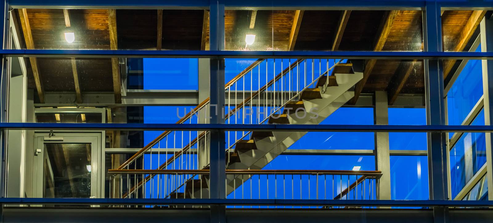 Stairs in a modern staircase building with glass windows, lighted at night, dutch architecture