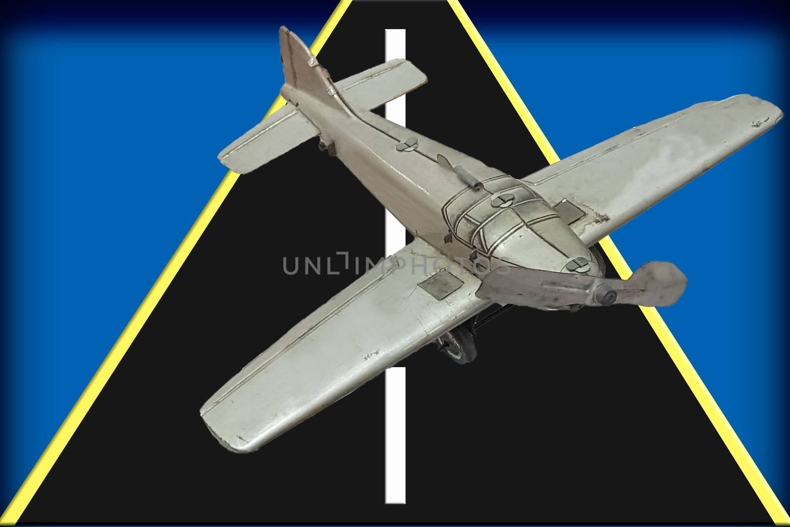 Image of a retro gray metal toy airplane with a runway in front of blue background.