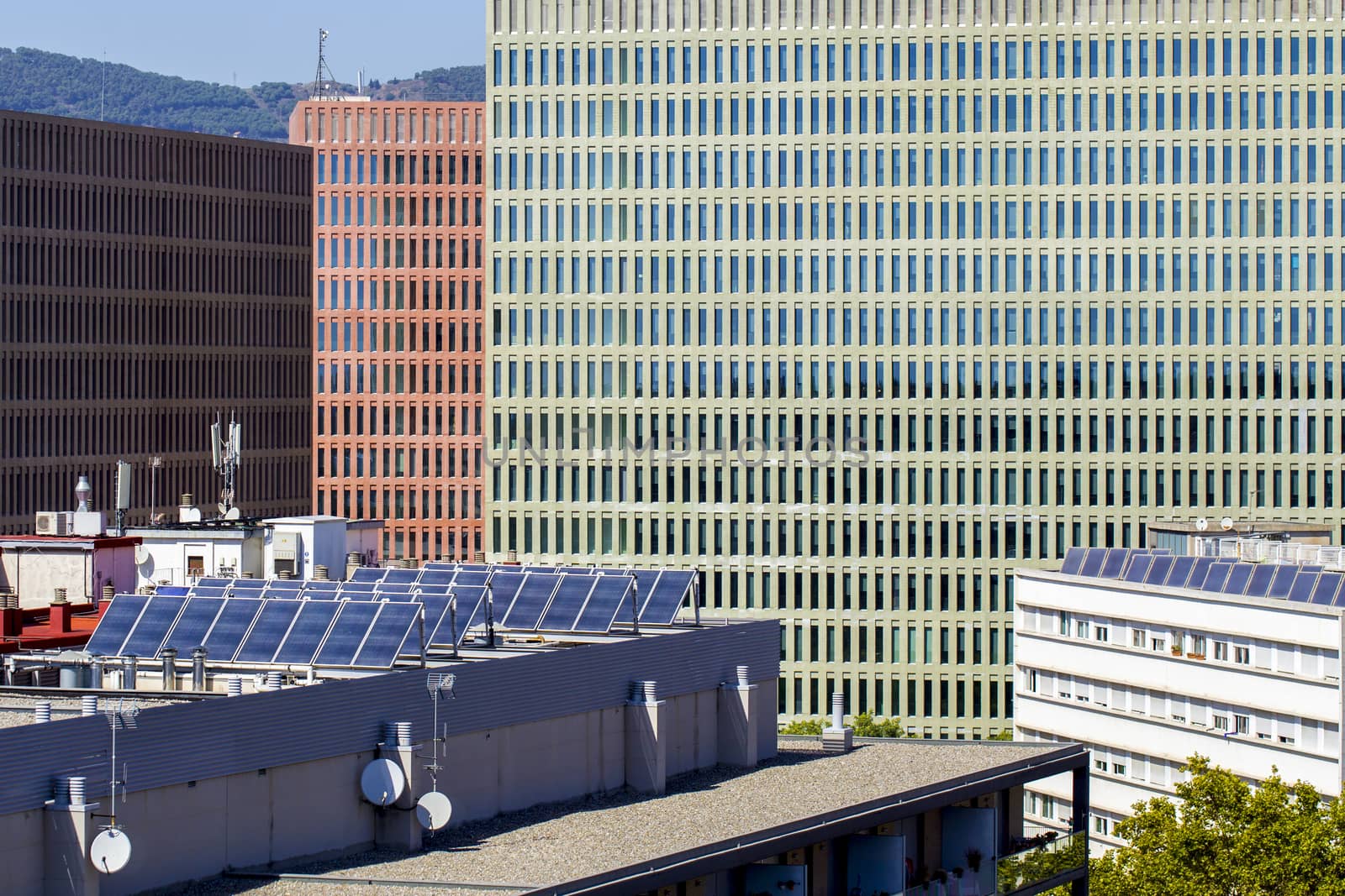 New residential buildings in Spain with solar panels on the roof to save energy. The facades of modern office buildings are visible behind.