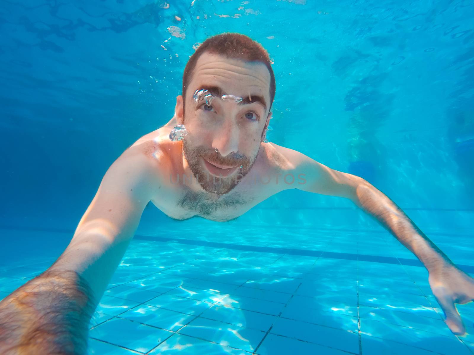 Young handsome man diving underwater in a swimming pool.