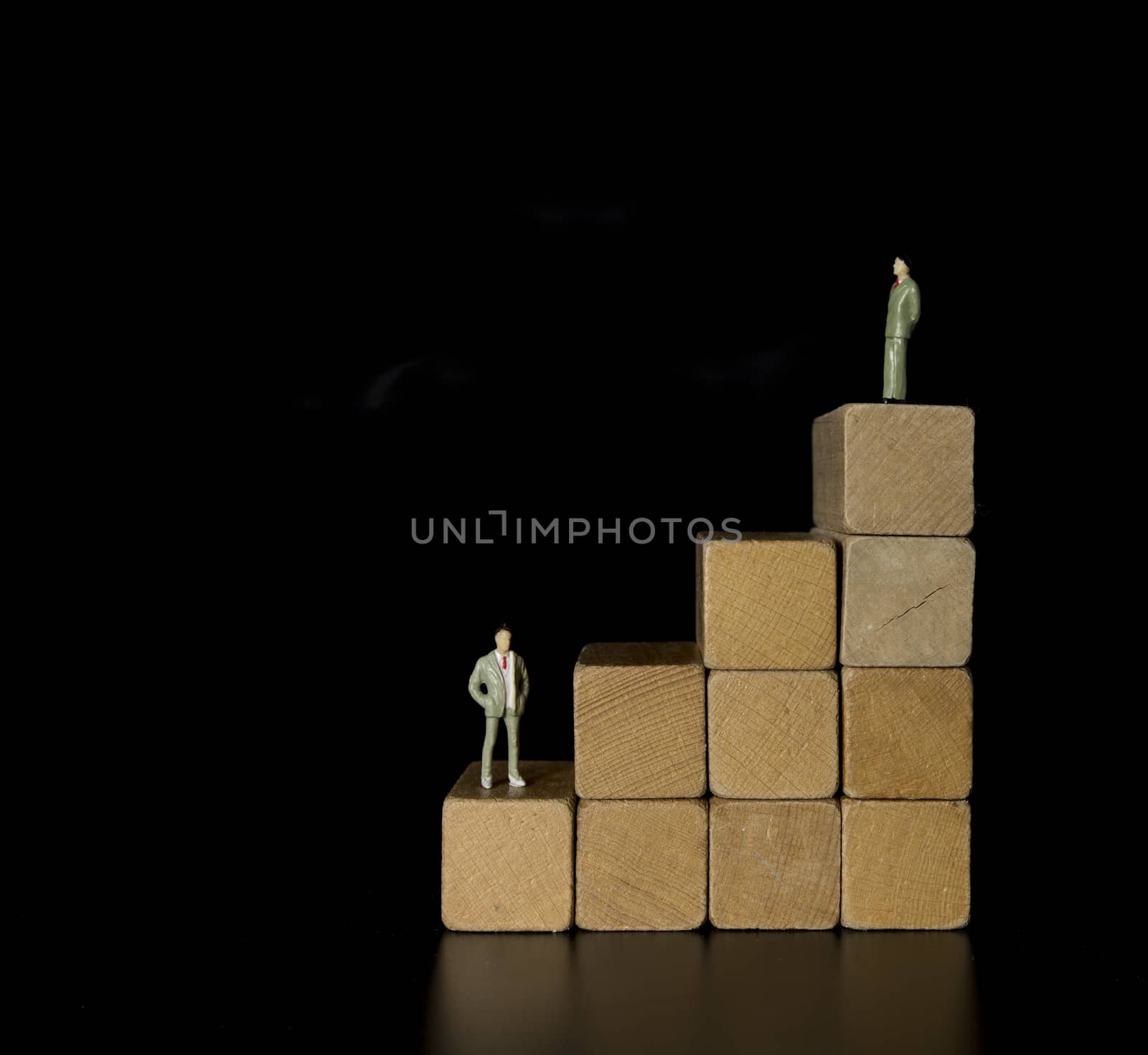 Wood block stacking as step stair with man on top of the career, Ladder career path concept for business growth success process on black background