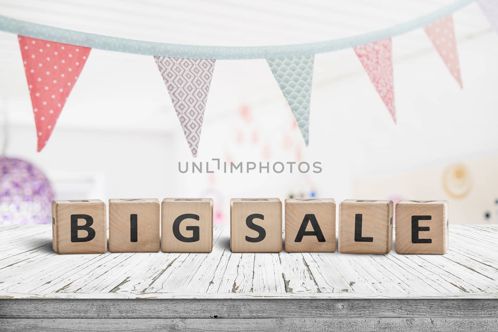 Big sale sign on a white table with festive flags hanging above