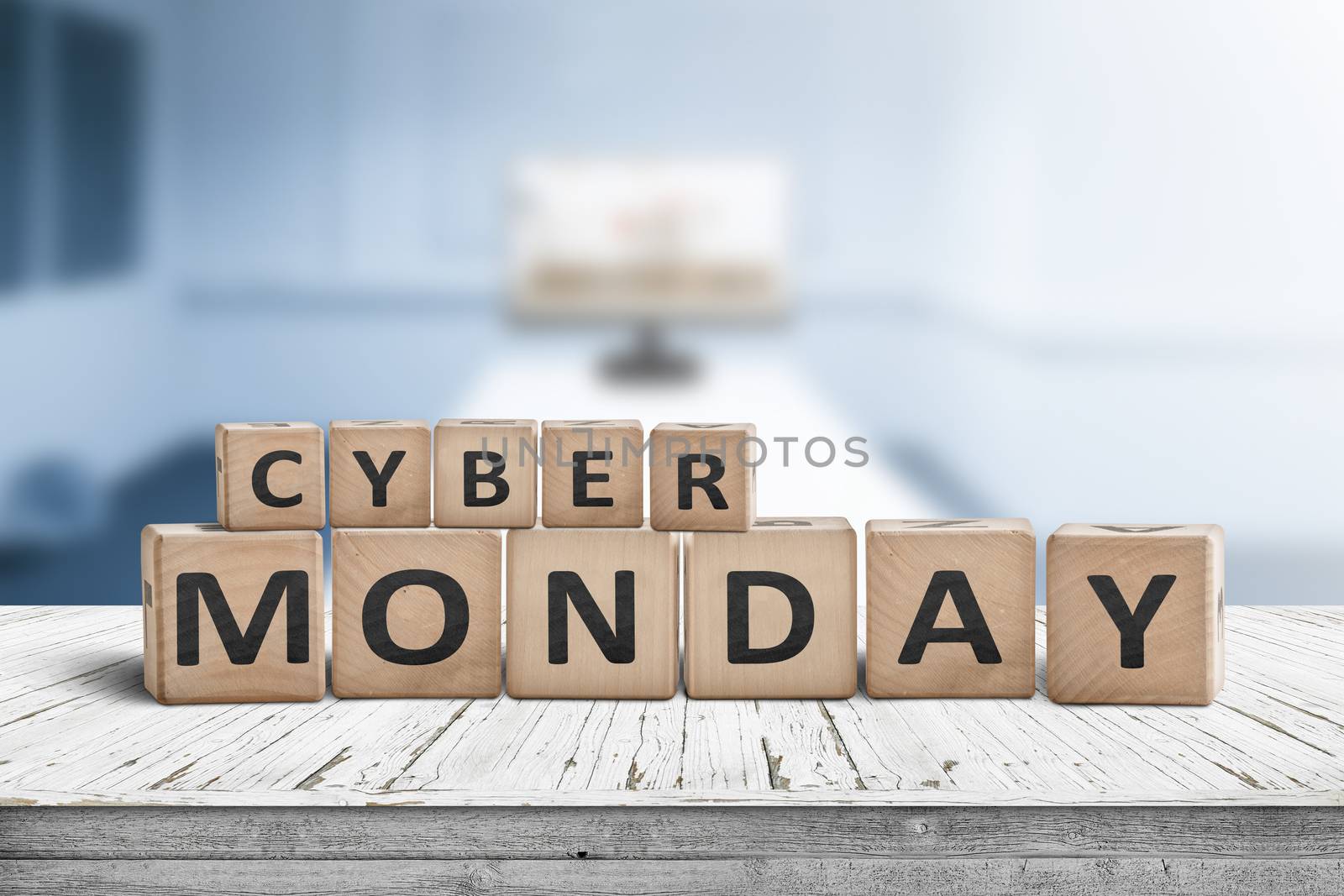 Cyber monday sign on a wooden desk with a monitor in a blue room in the background