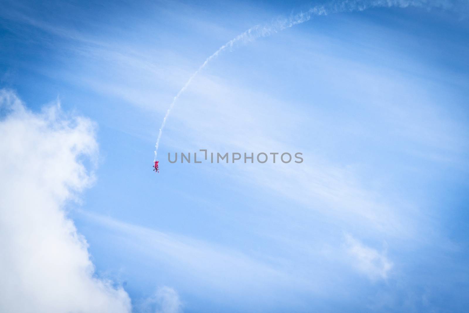 Veteran airplane makes a loop in the sky with smoke at its tail