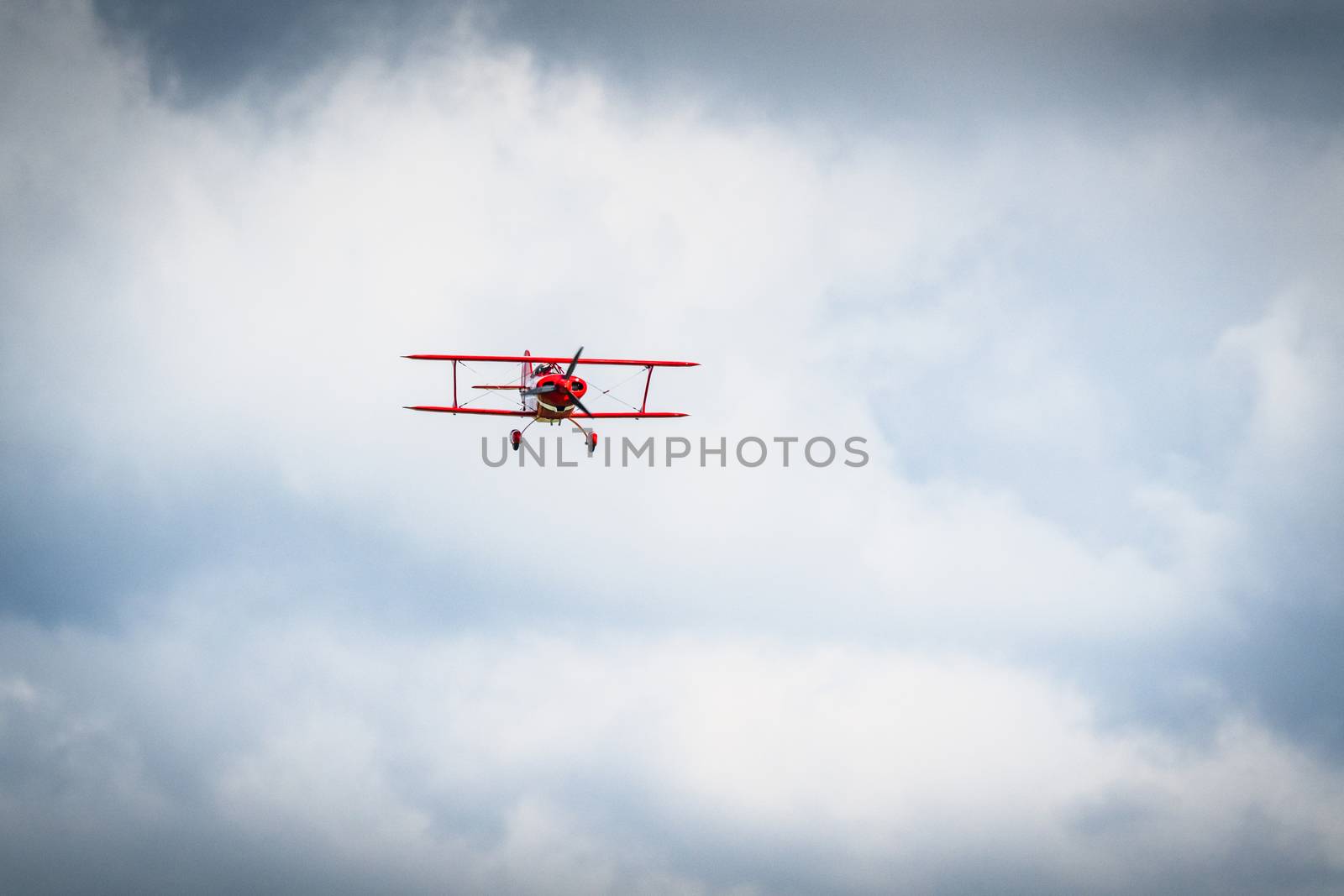 Vintage red propeller plane flying on a blue sky with front 