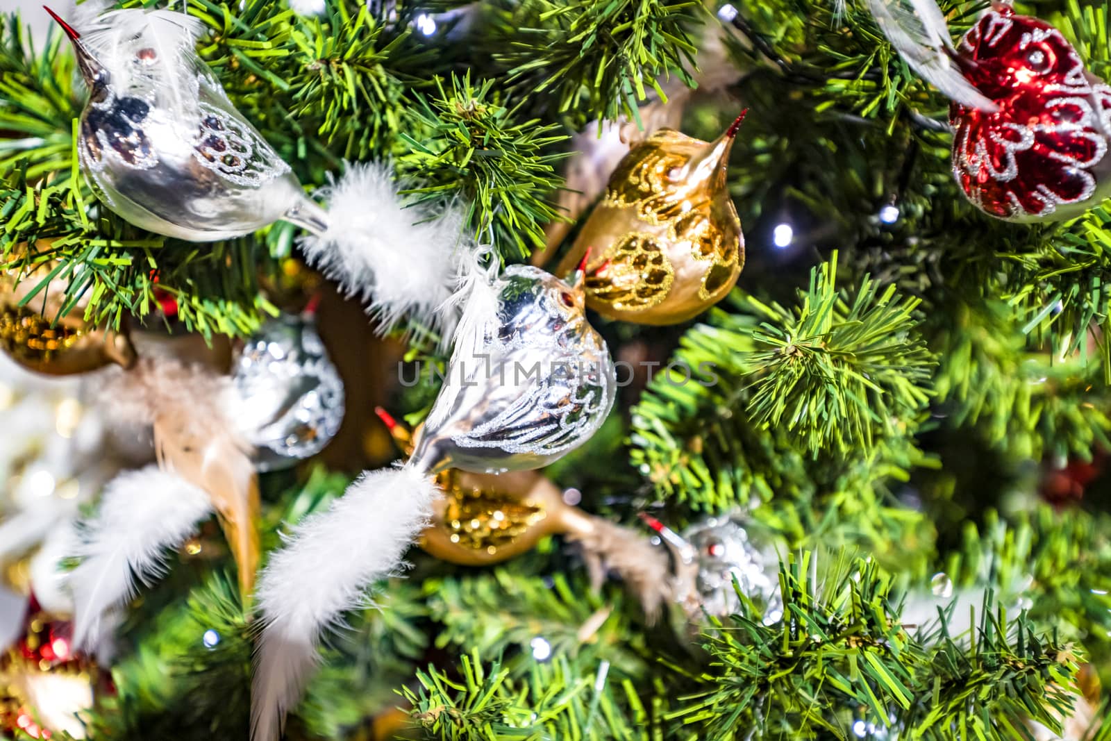 Christmas tree with bird baubles in silver glass in shiny lights