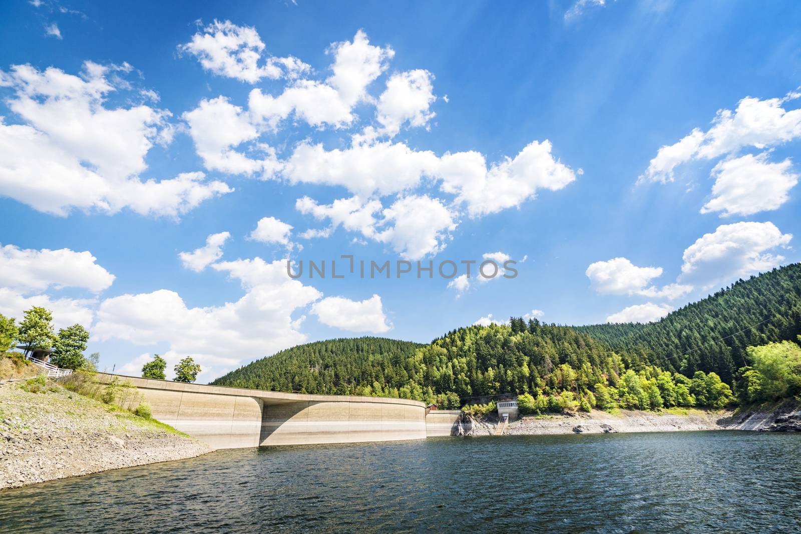 Lake landscape with a dam in summer with a forest in the background