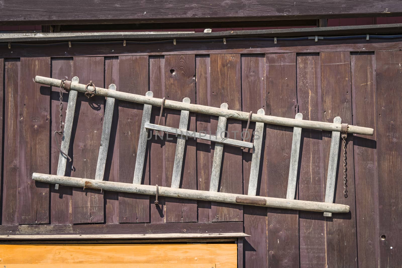 Wooden ladder hanging on the wall of a shed in the country