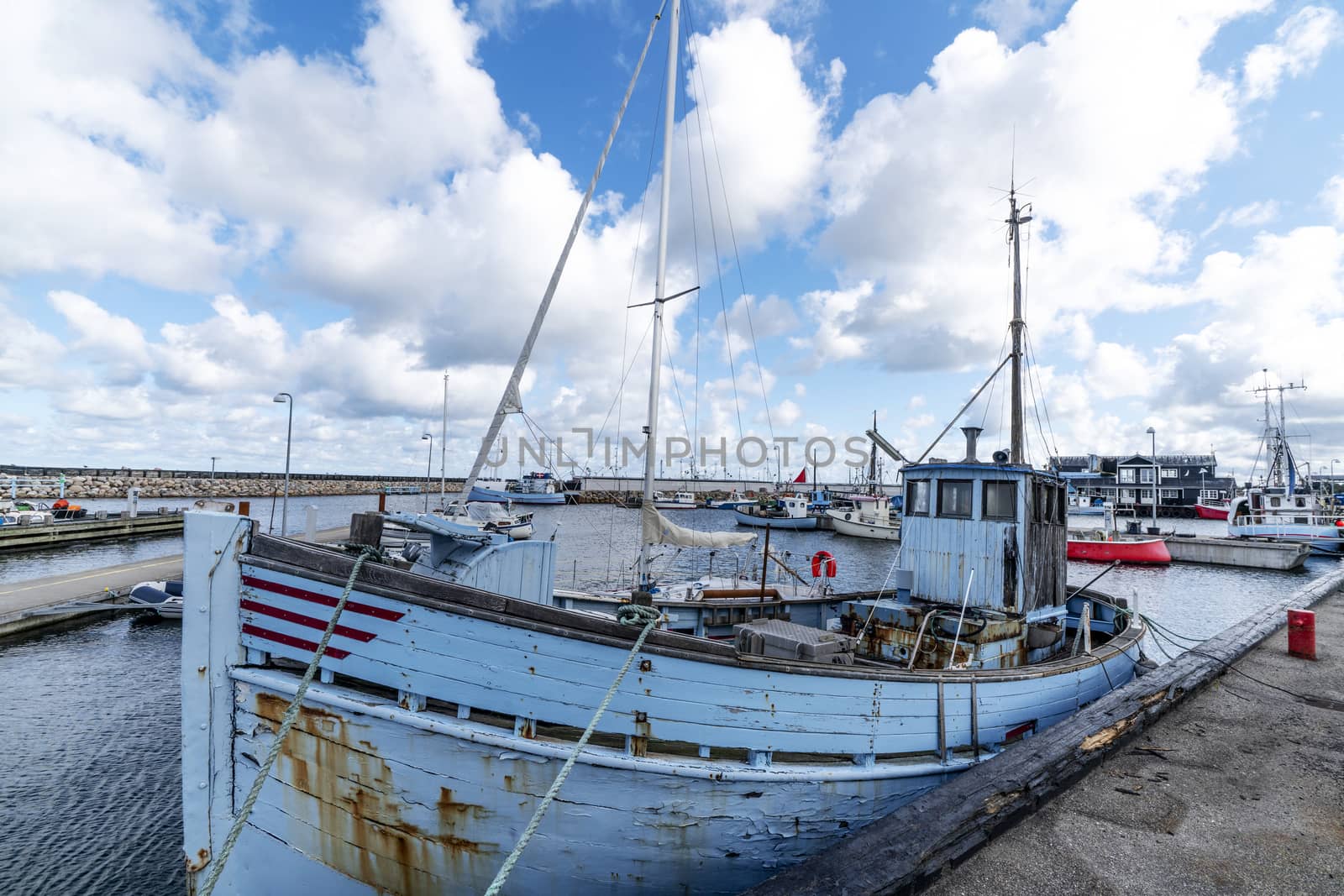 Old traditional fishing boat in a Scandinavian harbor under a cloudy blue sky