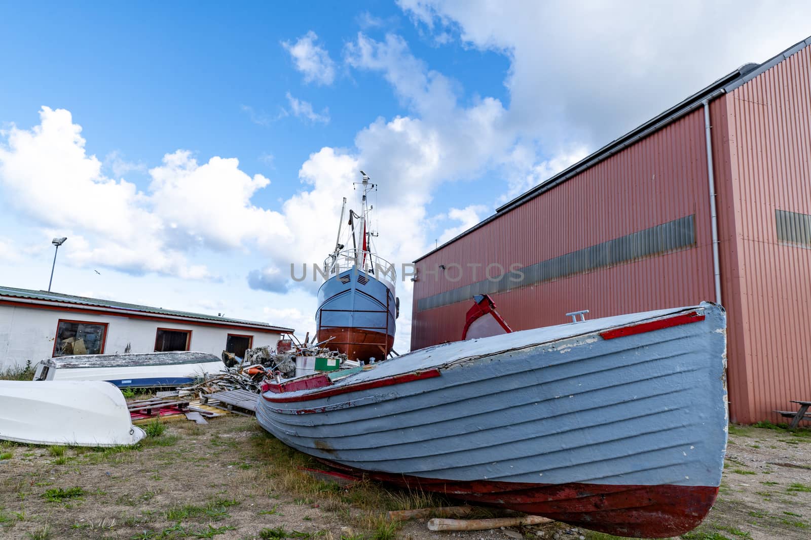 Wooden boat on land with a large ship in the background at the docks