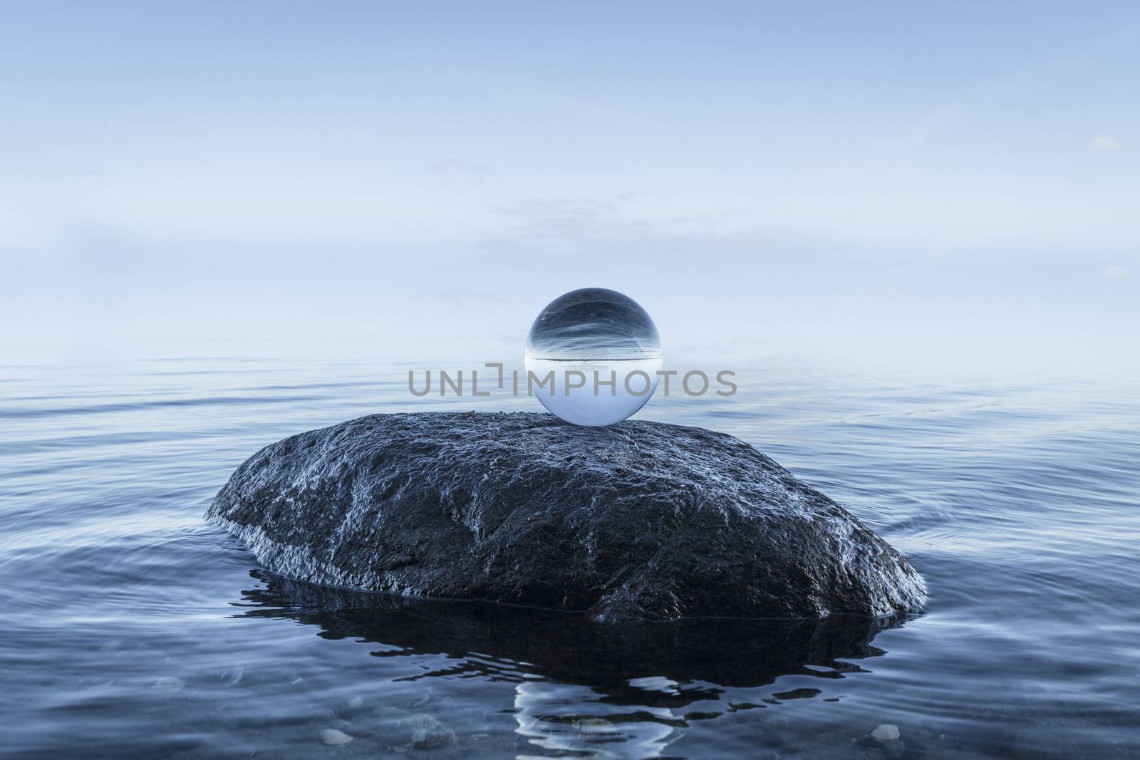 Crystal orb on a large black rock by the blue ocean on a silent morning