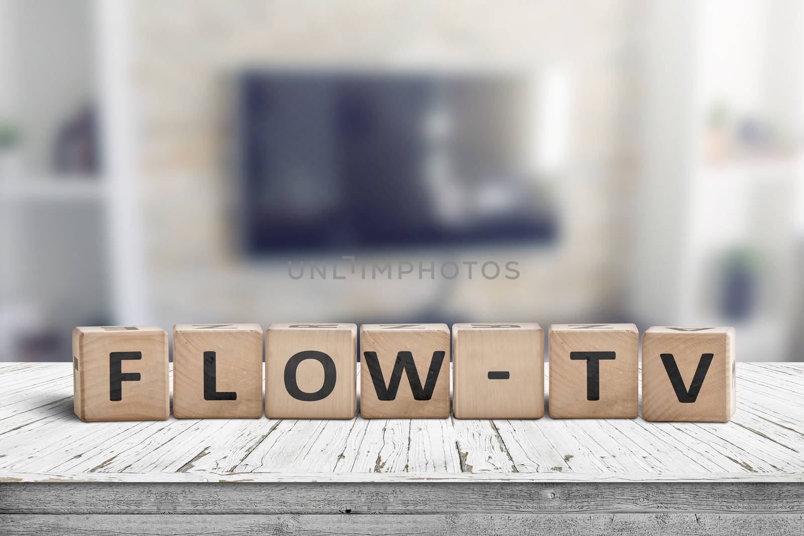 Flow-tv sign on a wooden table in a living room with a tv on the wall