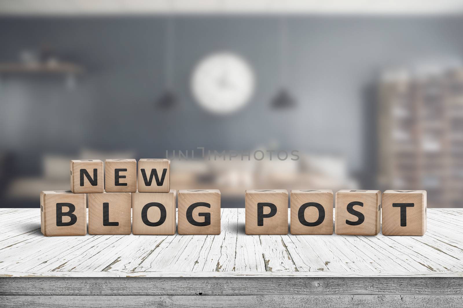 New blog post sign on a wooden desk with a stylish living room on a blurry background