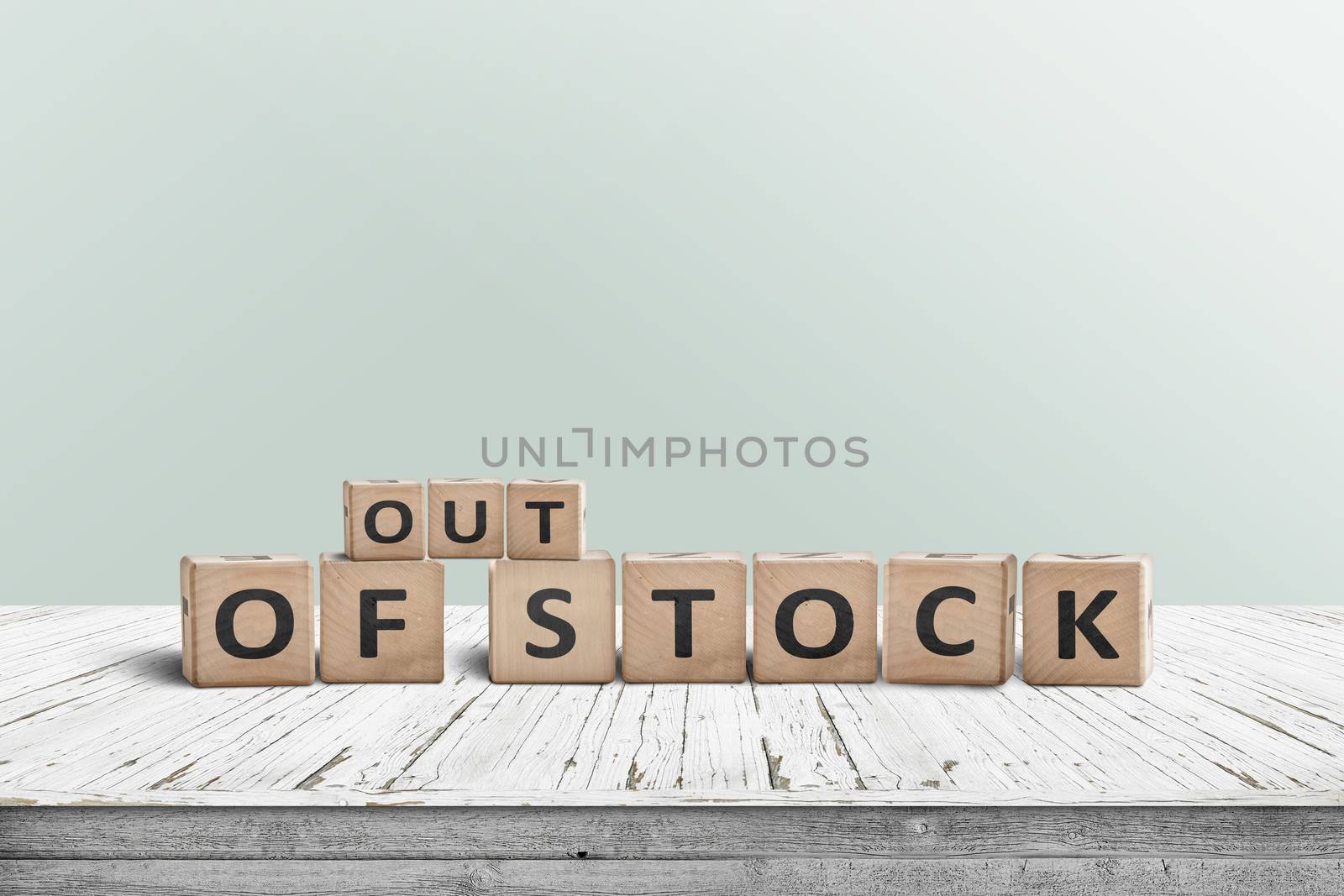 Out of stock sign standing on a wooden table with a green wall in the background