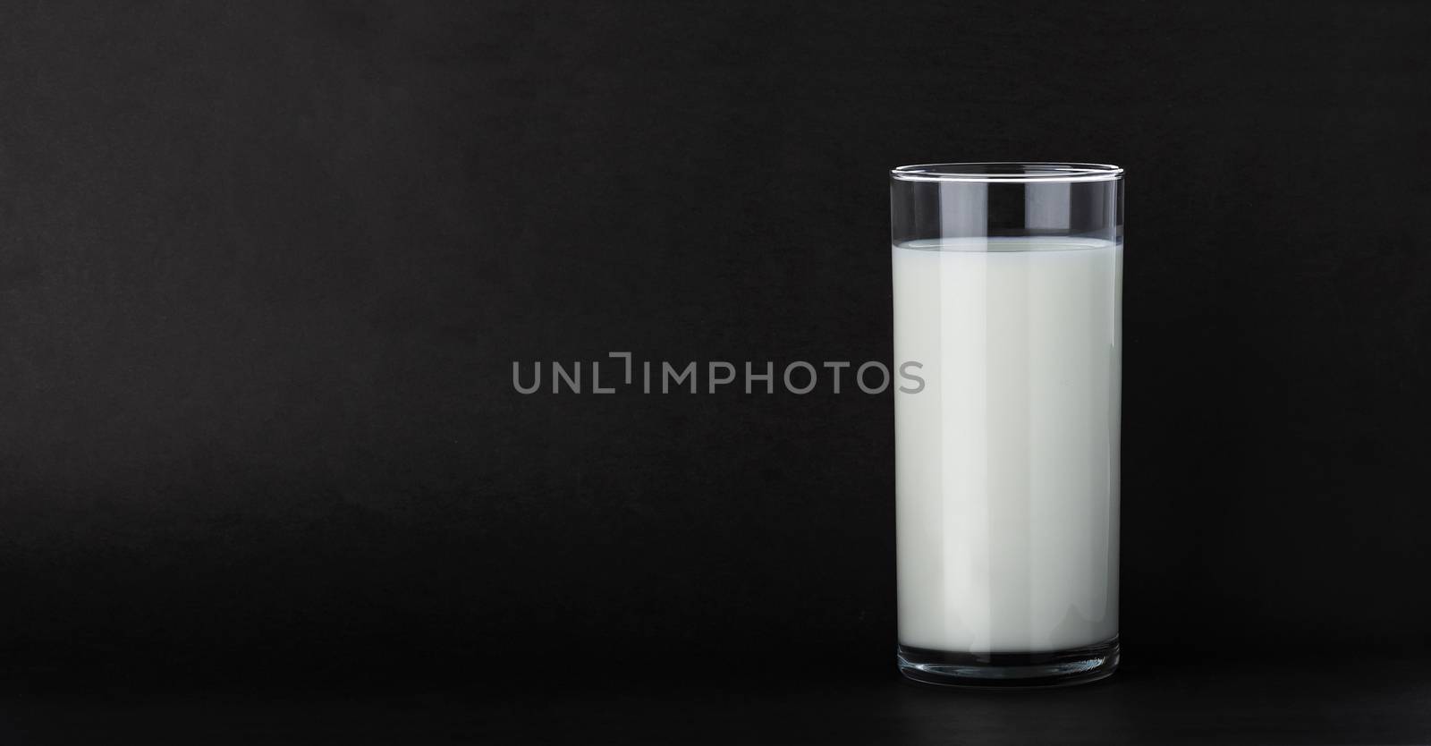 Glass of fresh milk isolated on black background with copy space
