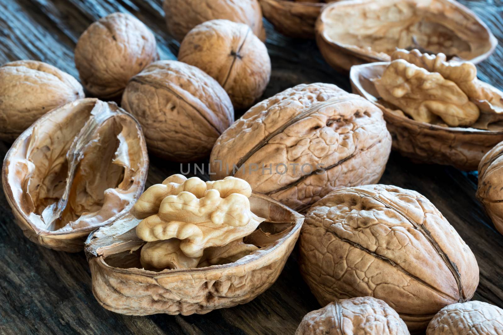 Closeup of whole and broken walnuts on a wooden background