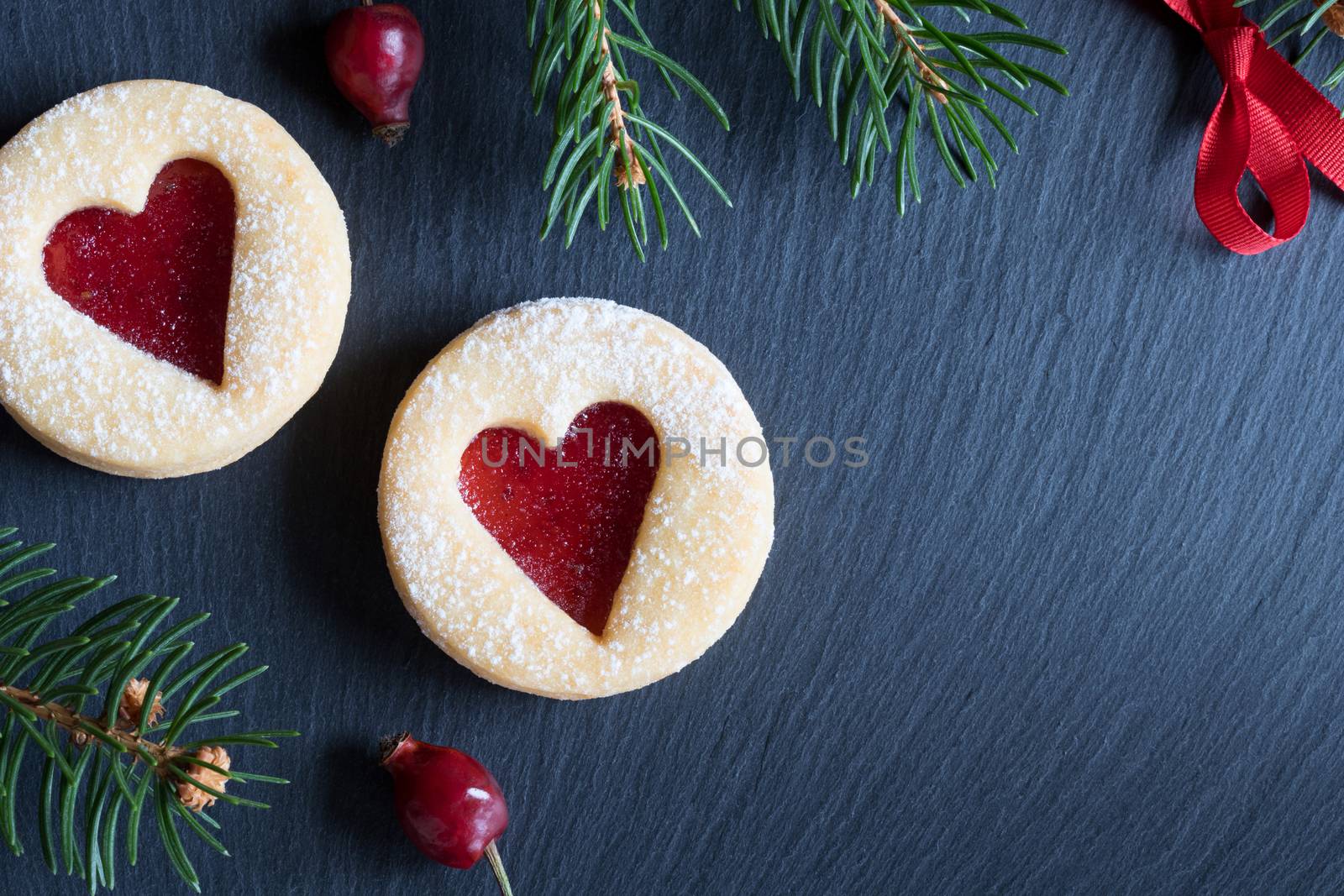 Christmas background with Linzer Christmas cookies, dried rose hips and spruce branches