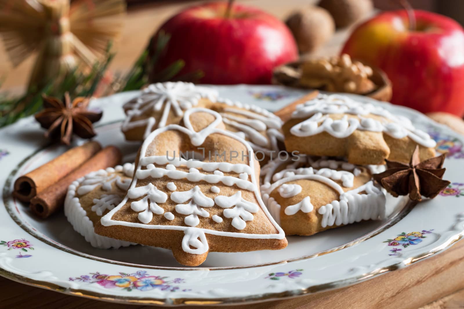 Christmas gingerbread cookies on a plate, with apples, spices and nuts in the background