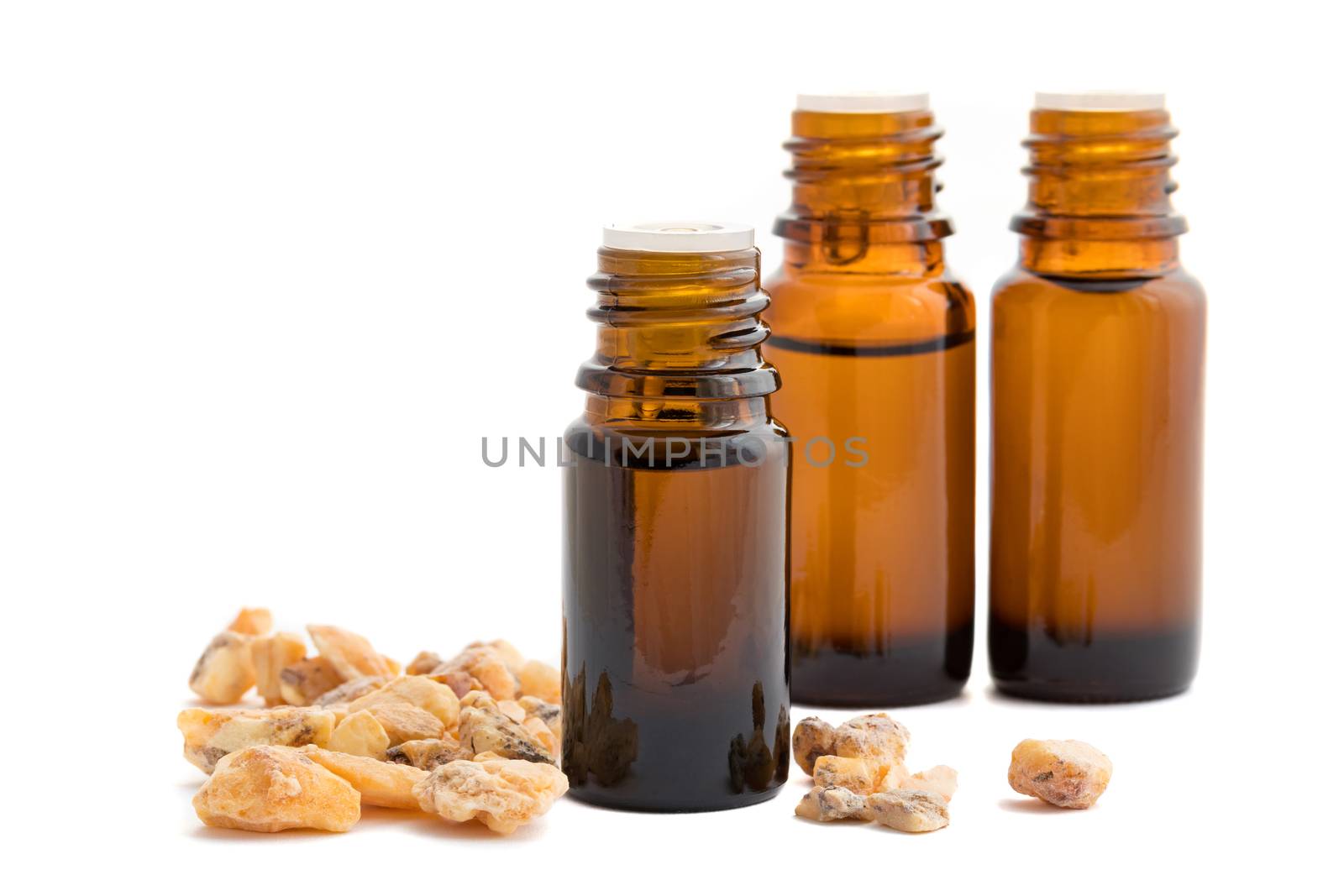 A bottle of styrax benzoin essential oil with styrax benzoin resin and other bottles on a white background