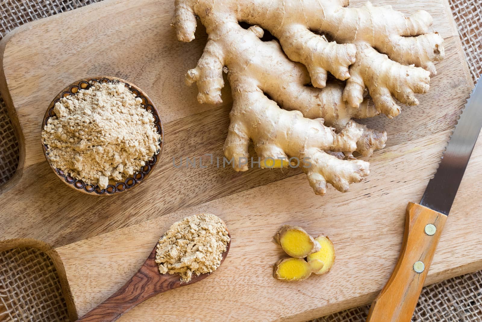 Ground and fresh ginger on a wooden background, top view