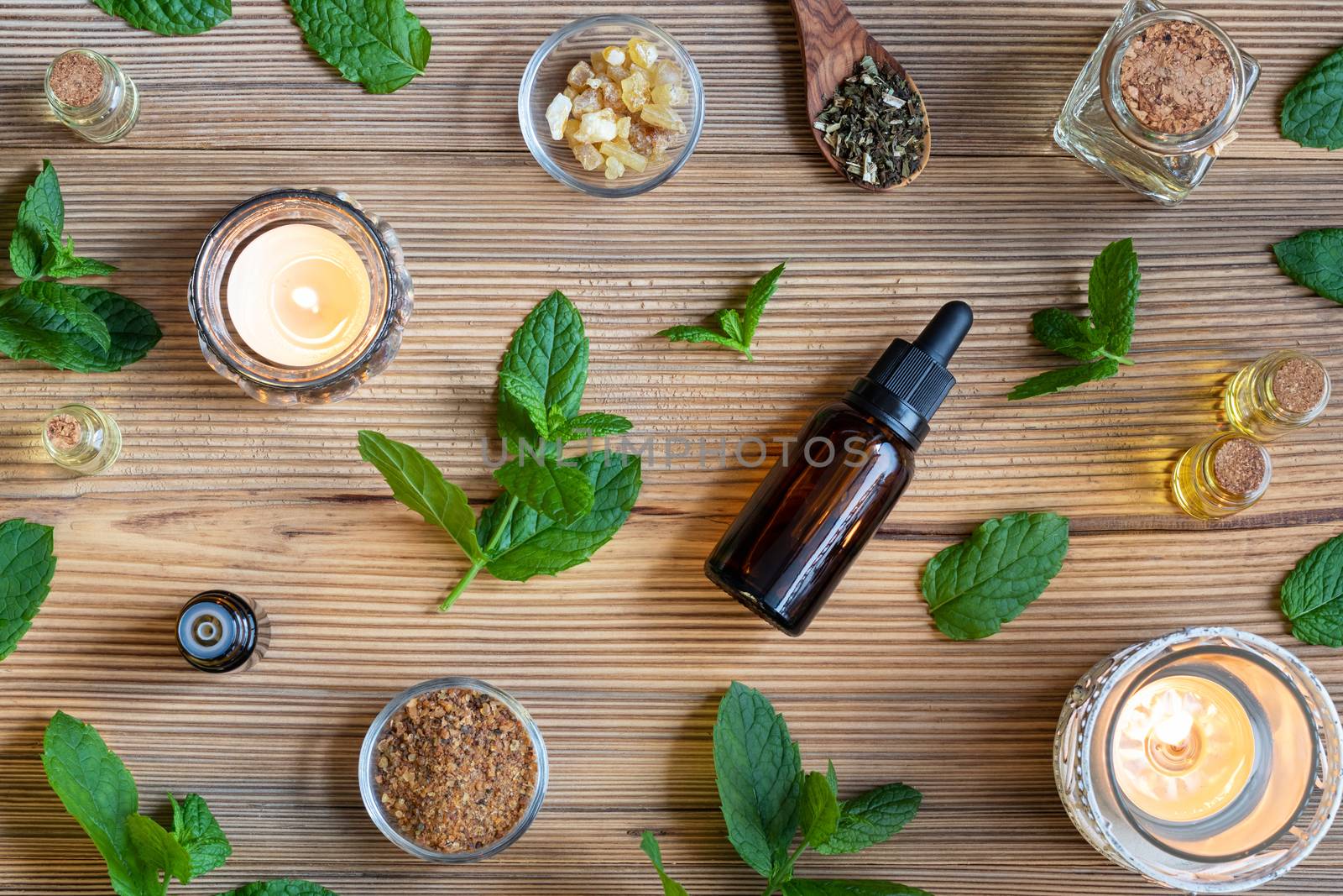 Bottles of essential oil with fresh peppermint, frankincense and myrrh