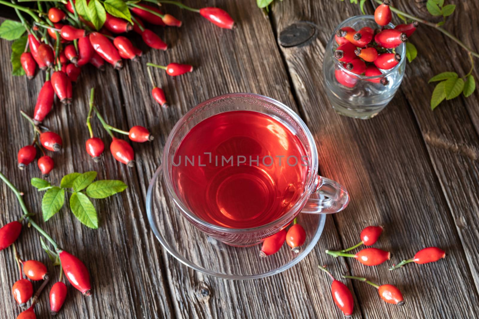 A cup of rose hip tea on a wooden table, top view