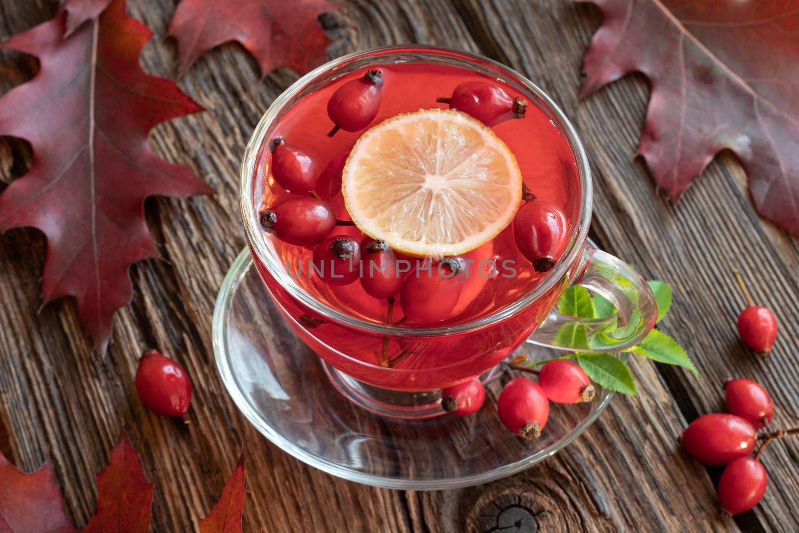 A cup of rosehip tea with autumn leaves on a table